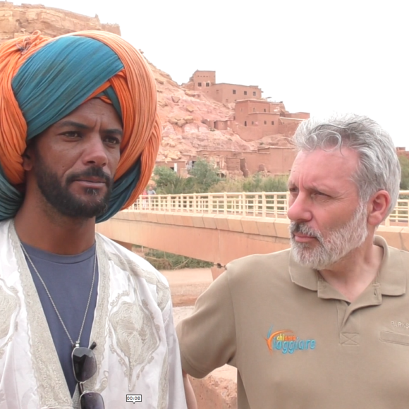 Walter Rubeo indossa la t-shirt ChiAma Viaggiare mentre parla con una comparsa del film Il Gladiatore ad Ait Ben Haddou.